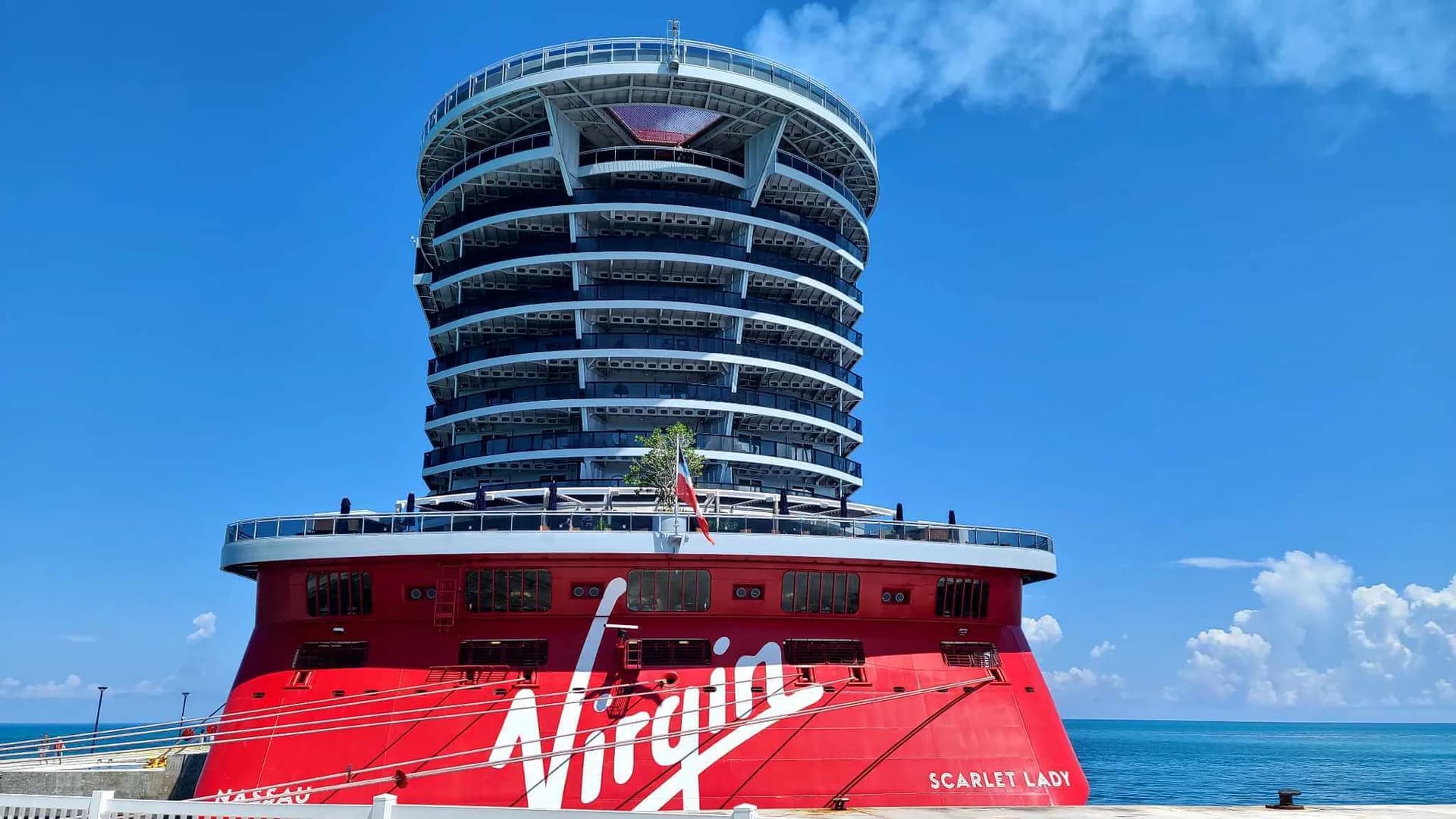 Scarlet Lady, Virgin Voyages' red-hulled cruise ship, docked under a clear blue sky