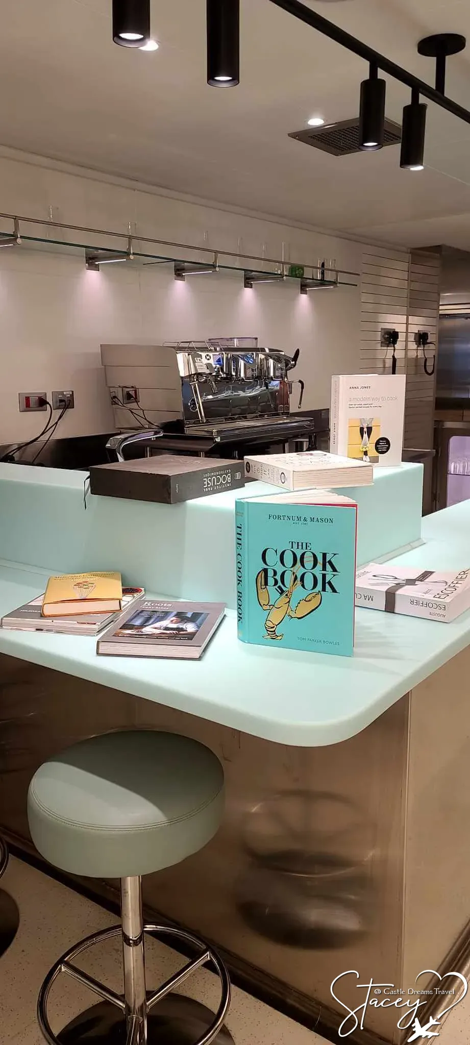 Cookbooks displayed on a counter beside an espresso machine aboard a Virgin Voyages ship