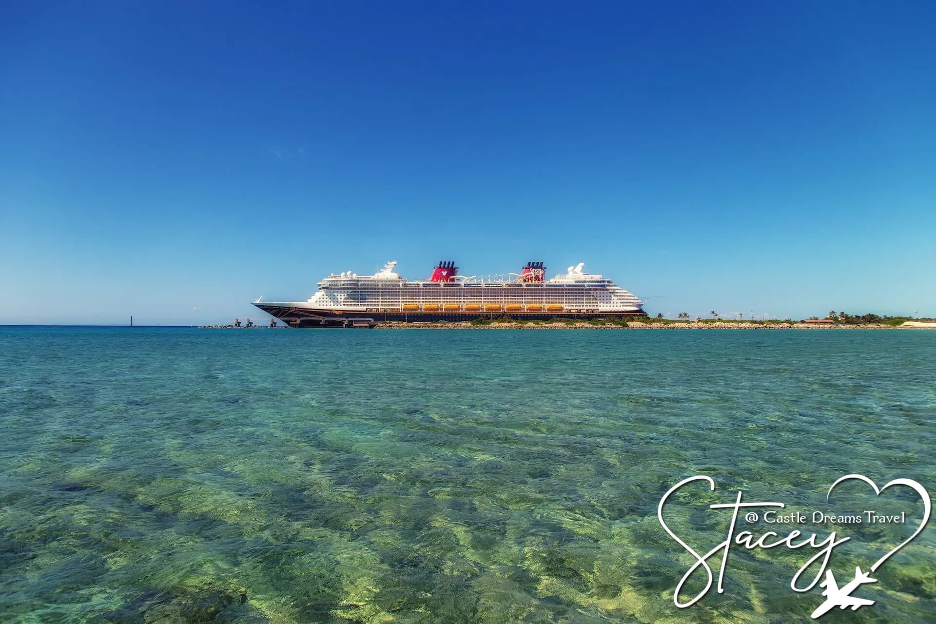 Disney Cruise Line ship at anchor off a white-sand island beach