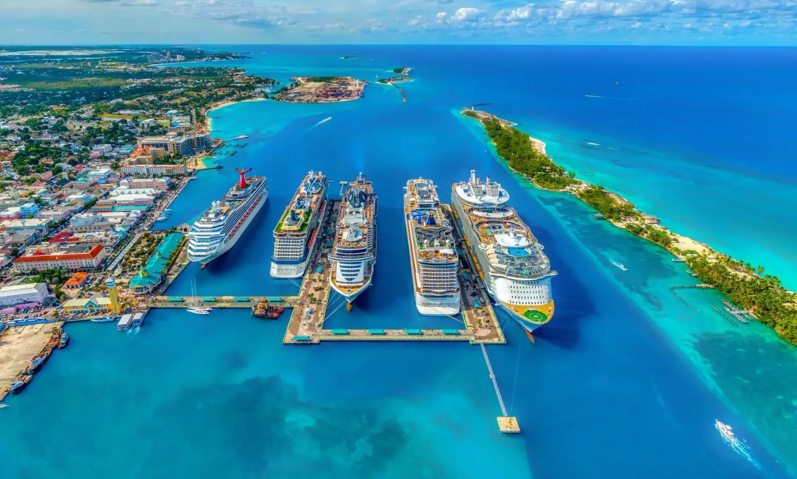 Aerial view of five cruise ships docked in a turquoise Caribbean harbor
