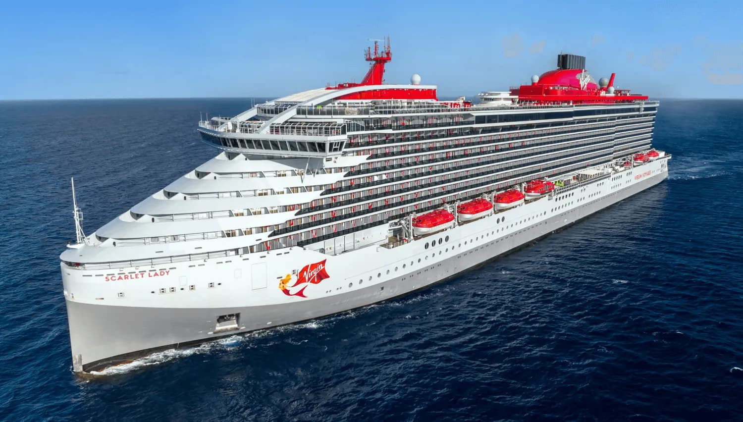 Virgin Voyages' Scarlet Lady at sea, with her grey hull, red funnel, and red Virgin logo