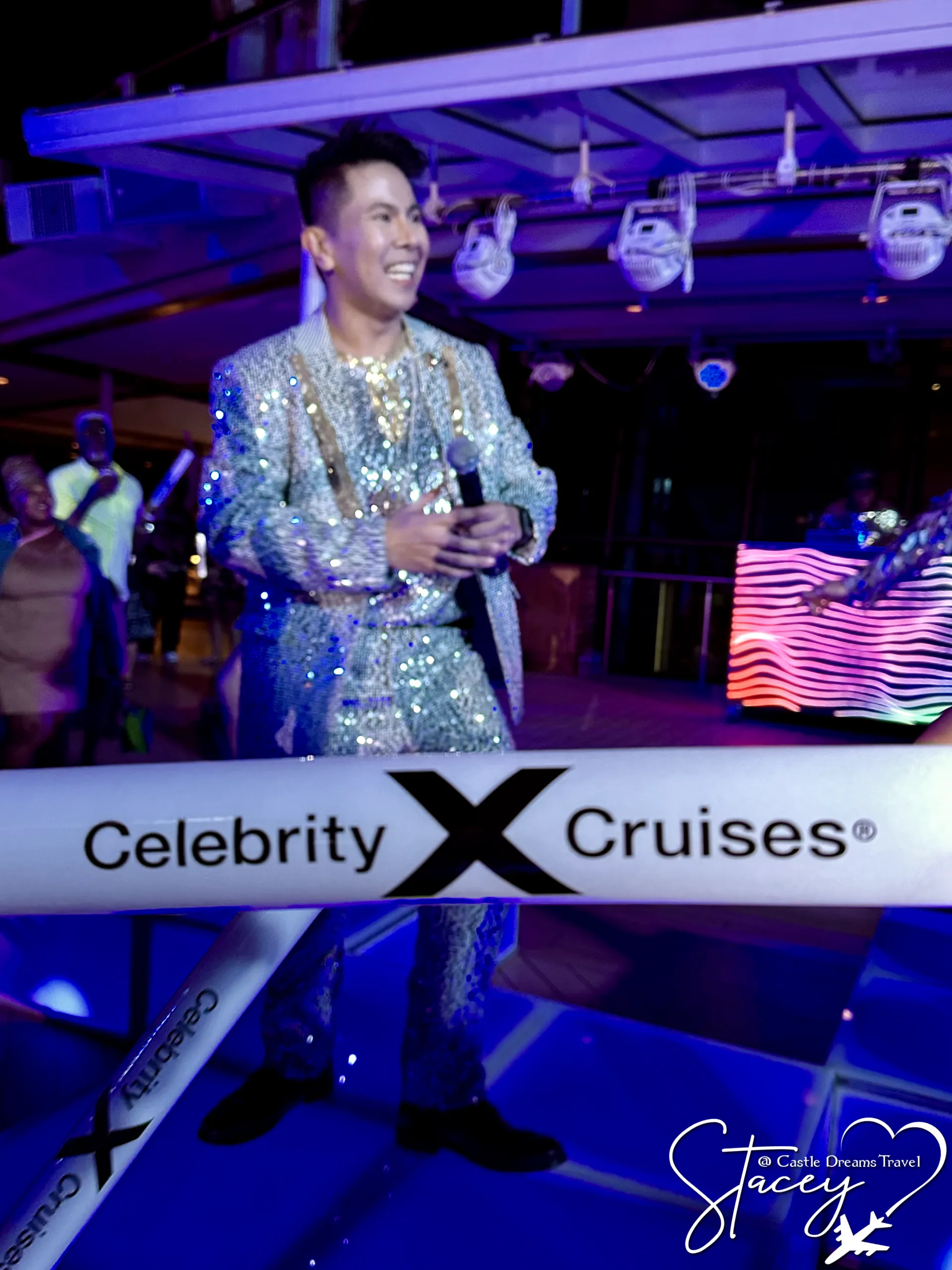 An entertainer in a sequined jacket performing with a microphone in a Celebrity Cruises onboard lounge