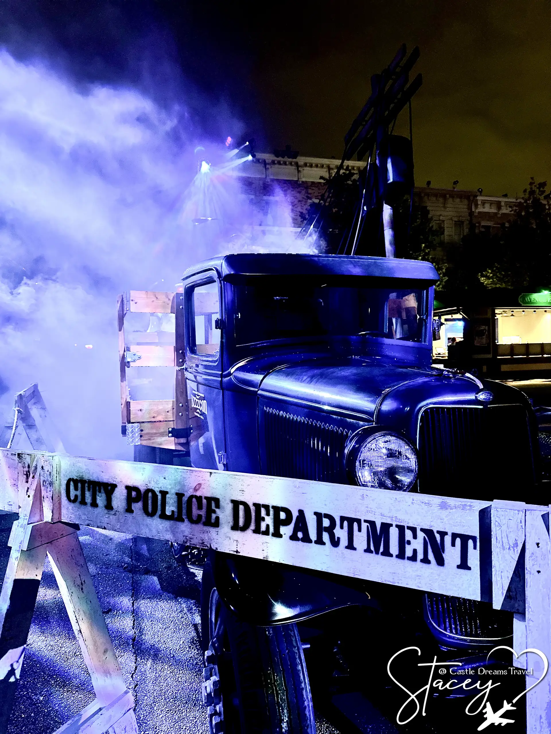 A vintage City Police Department truck staged in purple fog and spotlights in a scare zone