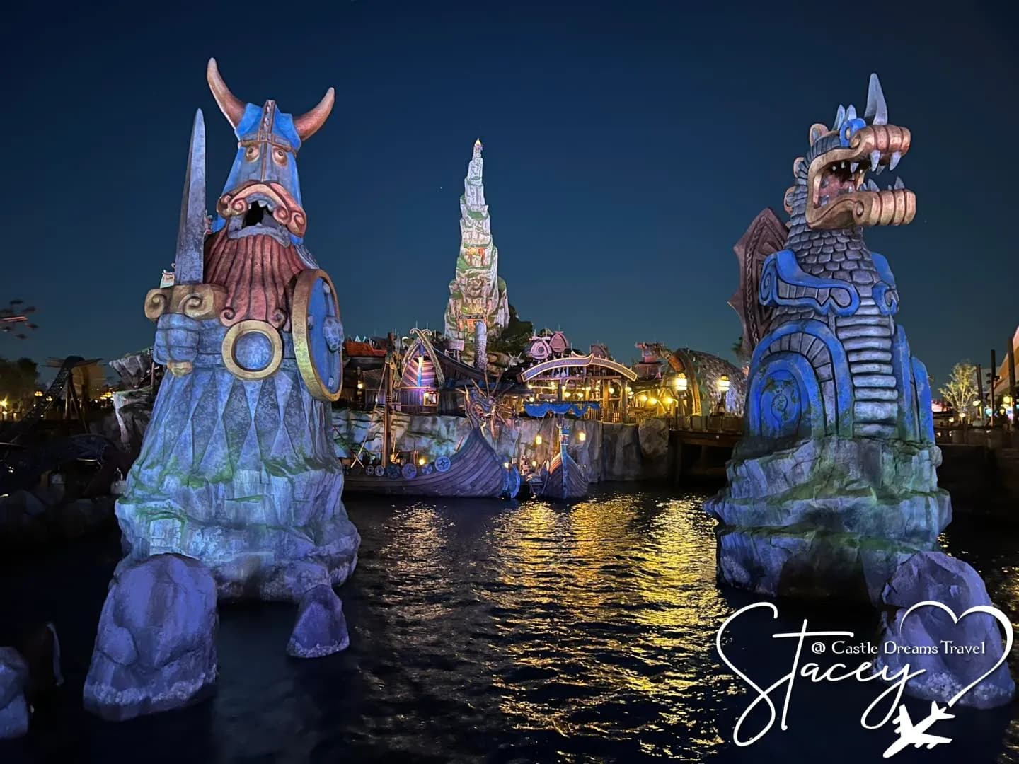 Viking statues flanking the water at the Isle of Berk in Epic Universe, lit up at dusk