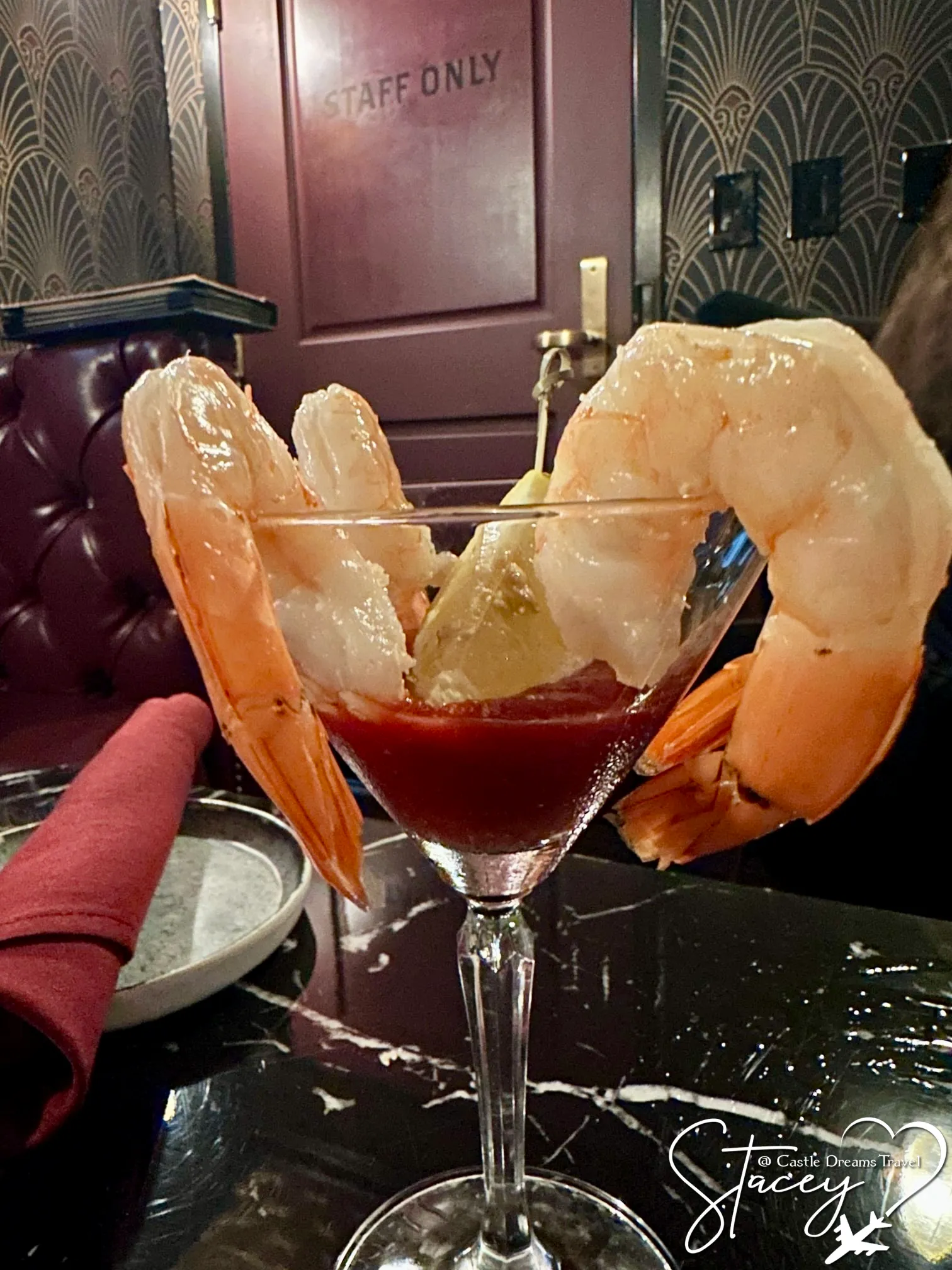 A shrimp cocktail served in a martini glass on a dark marble table