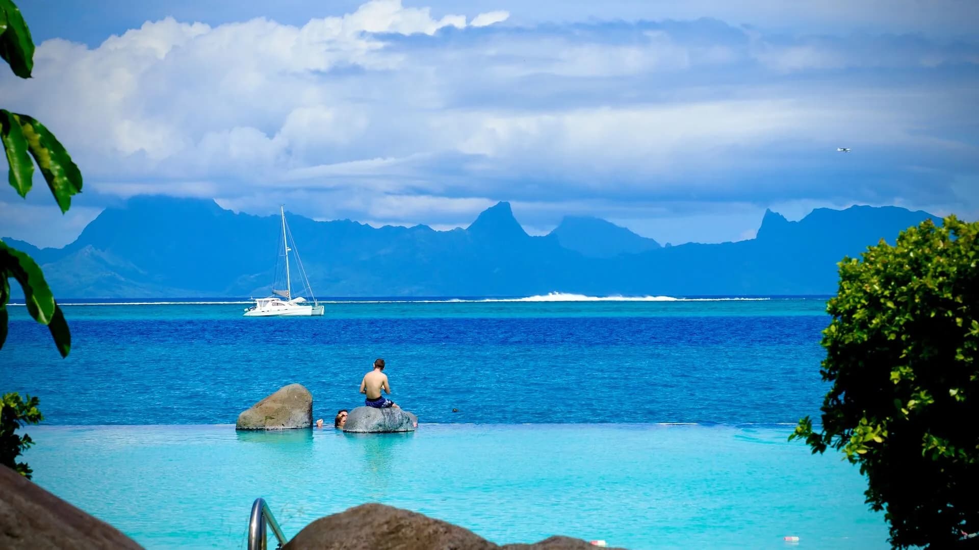 Catamaran on a turquoise lagoon in Tahiti with mountainous islands on the horizon