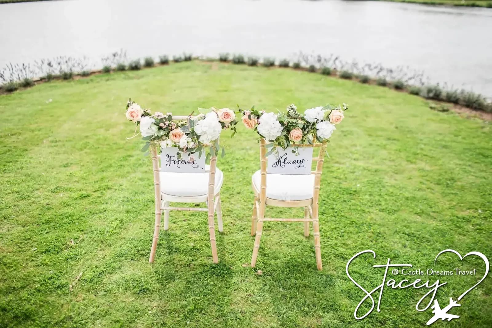 Two flower-decorated ceremony chairs labeled Forever and Always on a waterside lawn