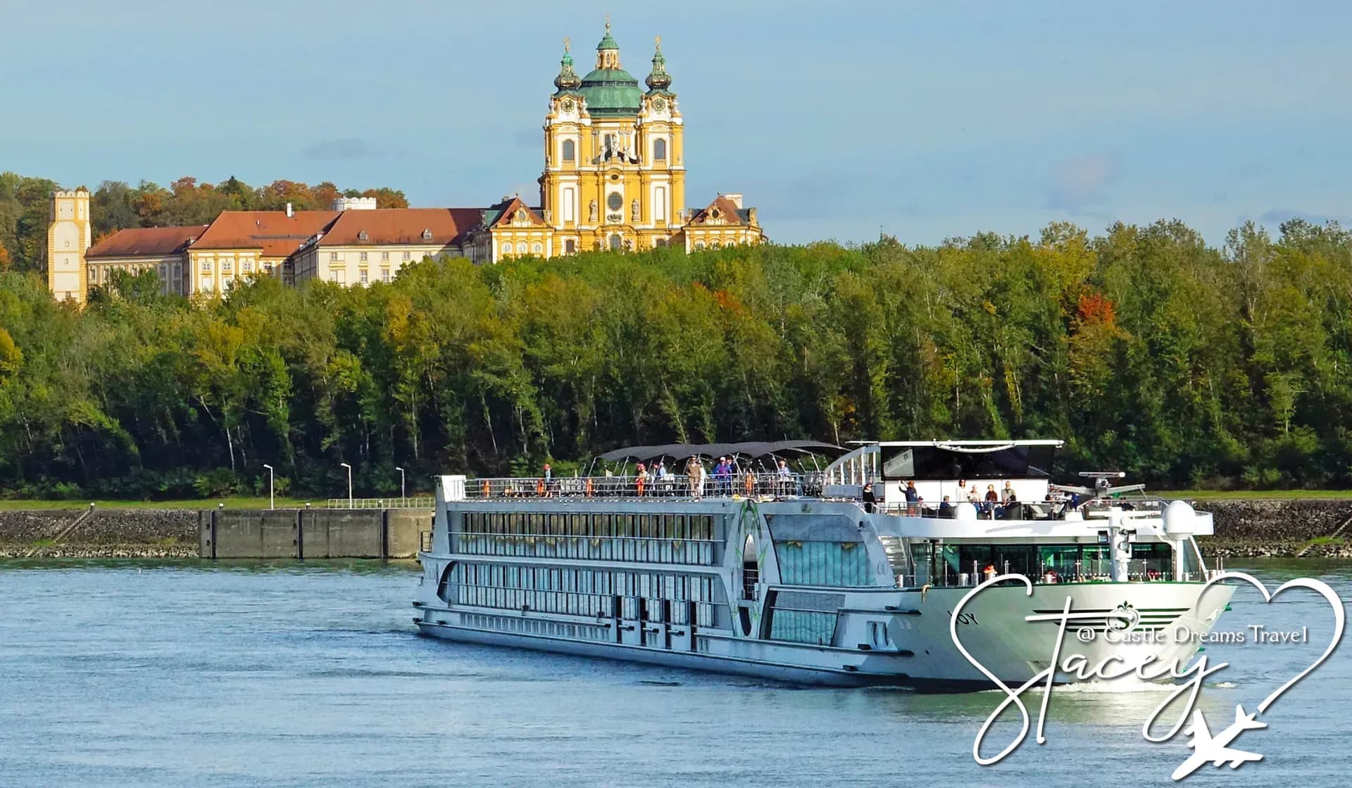 River cruise ship on the Danube passing below a hilltop baroque abbey